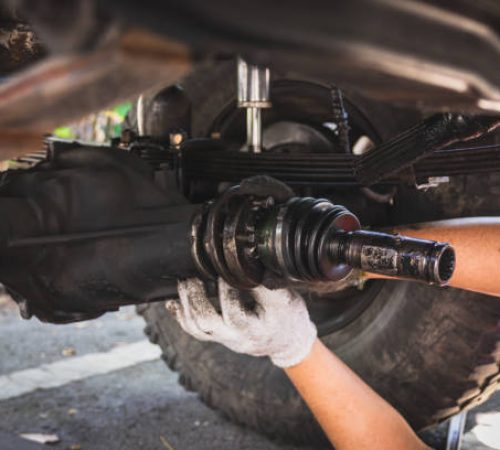 Technician's hand is wearing white cloth gloves, fixing the propulsion shaft of the car.